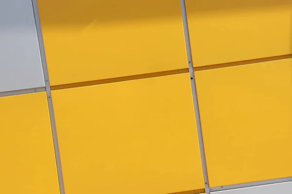 Close up of bright yellow wall with gray panels. Geometric background