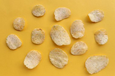 Sarı kağıtta patates cipsi deseni var. Üst görünüm, boşluğu kopyala. Düz zemin üzerinde yemek yatıyordu