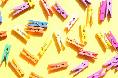 Sarı arka planda dekoratif çok renkli ahşap mandallar. Düz konum