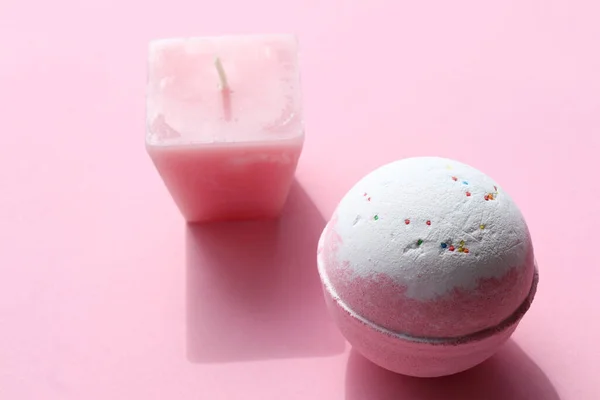 Spa composition with Bubble Bath Bomb, and candle on pink background. Pink salt bomb on pastel backdrop. Top view, copy space. Natural beauty spa body care product