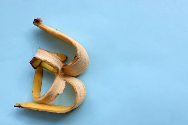 Mavi arka planda muz derisi. Gübrede muz kabuğu ya da ev yapımı gübre kullanmak. Sıfır atık. Üst görünüm, alanı kopyala