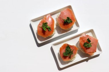 Krem peynirli ve maydanozlu füme somon kanapesi. Beyaz arka planda somonlu sandviç. Üst görünüm, alanı kopyala