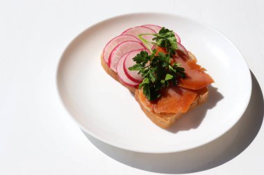 Füme somon, turp, krem peynir ve maydanozlu beyaz ekmek. Beyaz arka planda kahvaltıda sağlıklı tost tabağı. Üst görünüm, alanı kopyala