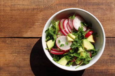 Avokadolu bir salata ve ahşap arka planda beyaz kasede turp. Üst görünüm