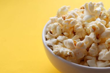 Sarı arka planda beyaz bir kasede patlamış mısır. Üst görünüm, alanı kopyala