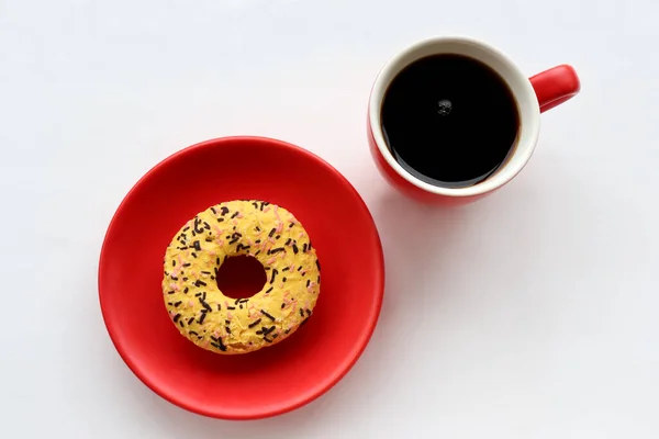 Red cup of coffee and a donut on white background. Top view, copy space. Flat lay food