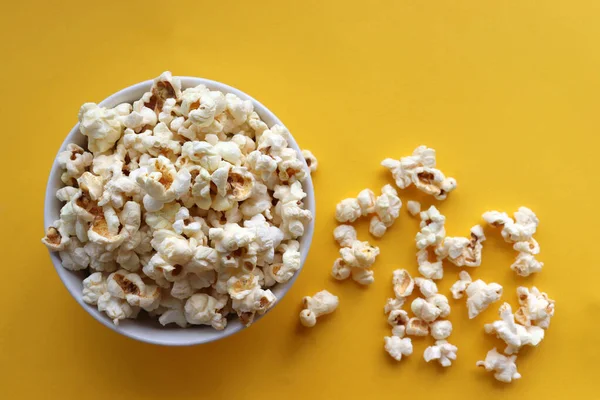 Sarı arka planda beyaz bir kasede patlamış mısır. Üst görünüm, alanı kopyala