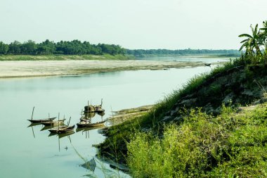 Nehir kıyısına bağlı küçük sandal botları var ve nehir suyu neredeyse kurumak üzereyken ve küresel ısınma yüzünden.