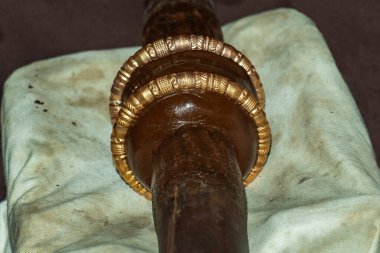 Dikkatle hazırlanmış bir bilezik ya da bilezik, düz, silindirik bir mandrel üzerine yerleştirilmiş koyu kahverengi cilalı metal, altın bantlar doğru düzenlenmiş