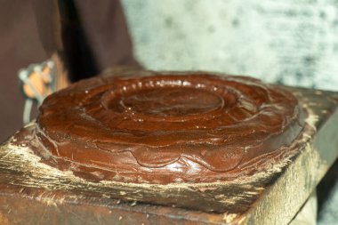 Yuvarlak, katmanlı ve koyu kahverengi bir tona ve parlak bir dokuya sahip bir nesne, eş merkezli halkalar, daha pürüzsüz bir üst yüzey, ve düzensiz, erime veya kalıpla oluşur.