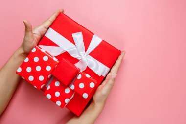 El ele tutuşmuş, hediye paketlenmiş ve pembeyle süslenmiş, arka planda izole edilmiş, fotokopi alanı olan bir kadın. Sevgililer Günü aşkı. Doğum günü teması.