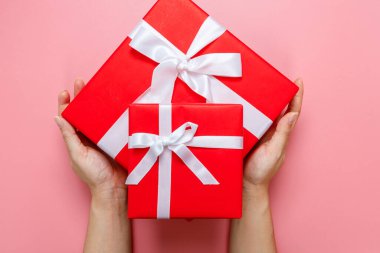 El ele tutuşmuş, hediye paketlenmiş ve pembeyle süslenmiş, arka planda izole edilmiş, fotokopi alanı olan bir kadın. Sevgililer Günü aşkı. Doğum günü teması.