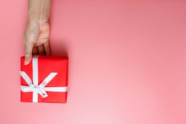 El ele tutuşmuş, hediye paketlenmiş ve pembeyle süslenmiş, arka planda izole edilmiş, fotokopi alanı olan bir kadın. Sevgililer Günü aşkı. Doğum günü teması.