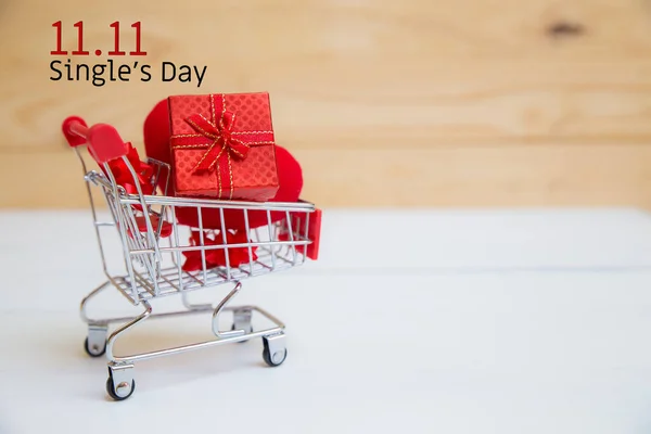 Online shopping of China, 11.11 single\'s day sale concept. The shopping cart and red heart pillow on white and brown background with copy space for text 11.11 single\'s day sale.