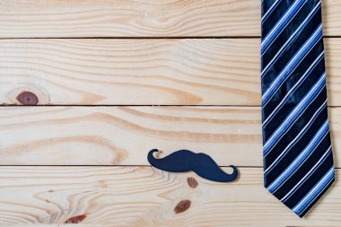 Babalar günün kutlu olsun. Siyah bir bıyık kağıdı, mavi bir kravat ve tahta masada gözlük..