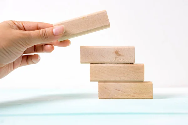 Hand arranging wood block stacking as step stair. Business concept for growth success process. Stairs up as a symbol of career growth up or business success.