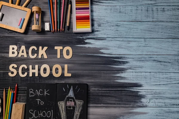 School supplies on black board background. Back to school concept.