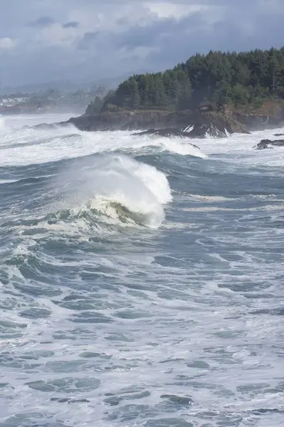 big ocean waves, water splashes at rocky cliffs
