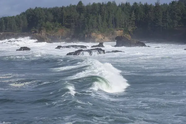 big ocean waves, water splashes at rocky cliffs