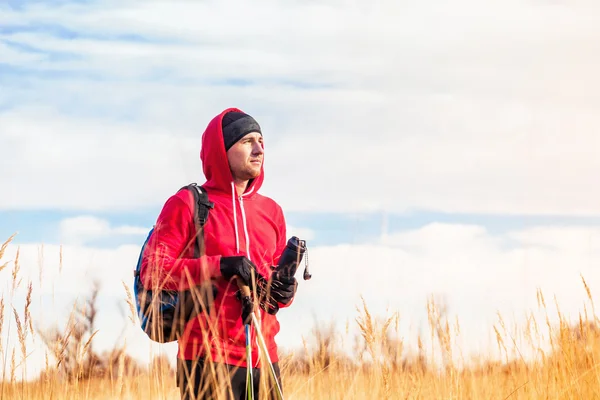 Turysta człowiek z plecaka stoi w polu i patrząc na krajobraz malowniczego pola — Zdjęcie stockowe