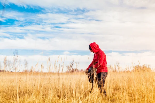 Caminante parado en el campo y poniendo su botella de agua dentro de una mochila — Foto de Stock