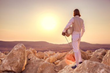 Fencer adam üstüne maske ve gün batımı arka plan üzerinde bir kılıç eskrim kaya holding ayakta