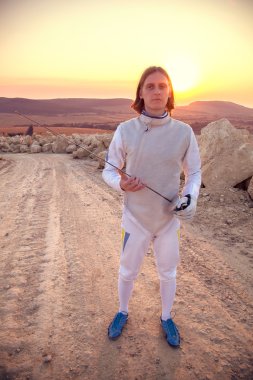 Fencer adamın beyaz kostüm holding kılıç eskrim ve ileriye dönük giydiğini