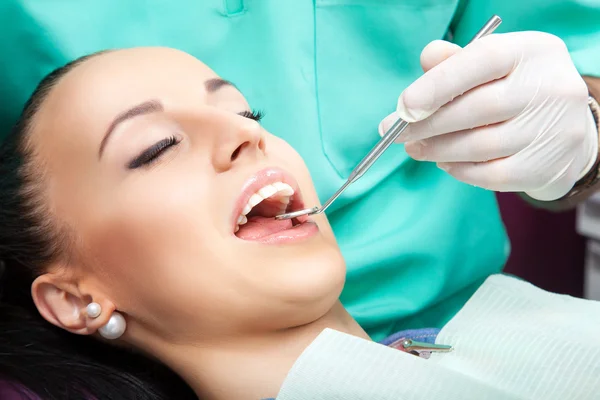 Mulher sentada na cadeira do dentista enquanto o médico examina os dentes — Fotografia de Stock