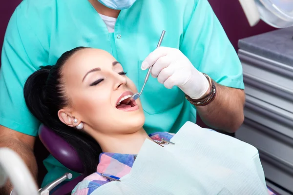 Mujer sentada en silla dental mientras el médico examina sus dientes —  Fotos de Stock