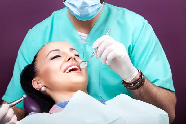 Mulher sentada na cadeira dentária enquanto médico examinando seus dentes . — Fotografia de Stock