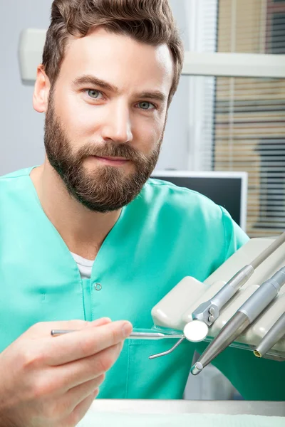 Médico varón con barba en traje verde en clínica dental — Foto de Stock