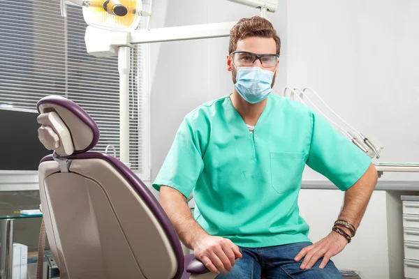 Jovem bonito masculino médico vestindo dentista máscara e óculos . — Fotografia de Stock