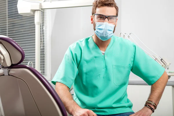 Jovem bonito masculino médico vestindo dentista máscara e óculos . — Fotografia de Stock