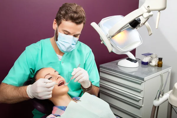 El dentista masculino examina la boca de la mujer en la silla del dentista —  Fotos de Stock