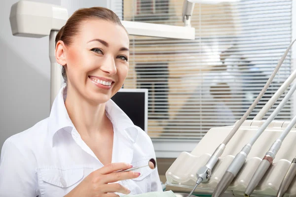 Jovem bela médica sorrindo segurando espelho dental — Fotografia de Stock