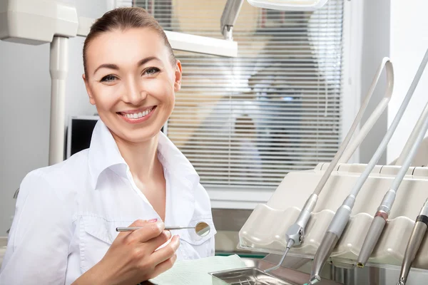 Jovem bela médica sorrindo segurando espelho dental — Fotografia de Stock