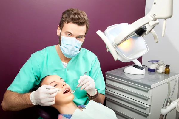 El dentista masculino examina la boca de la mujer en la silla del dentista —  Fotos de Stock