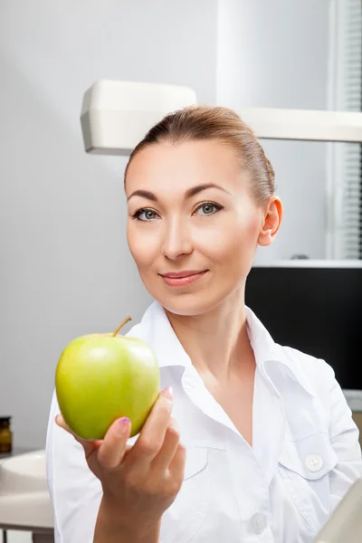 Joven hermosa mujer médico sonriendo sosteniendo verde manzana fresca —  Fotos de Stock