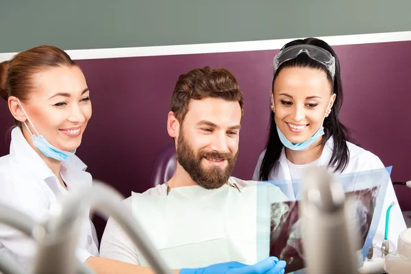 Женщина-врач и ее улыбающаяся ассистентка показывают рентген зубов — стоковое фото