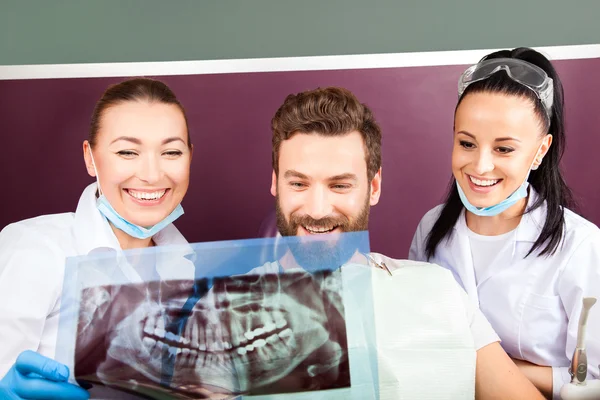 Female doctor and her smiling assistant showing teeth x-ray — Stock Photo, Image
