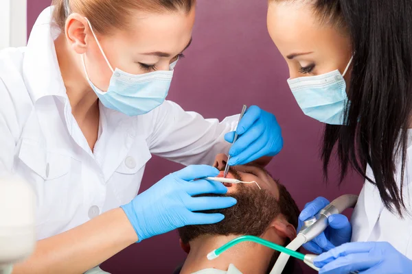 Mujer dentista médico hace revisión de dientes para los hombres pacientes —  Fotos de Stock