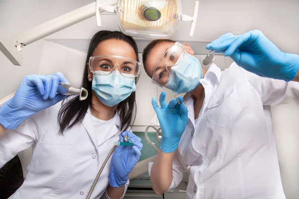 Doctora dentista y asistente en máscaras mirando a la cámara —  Fotos de Stock