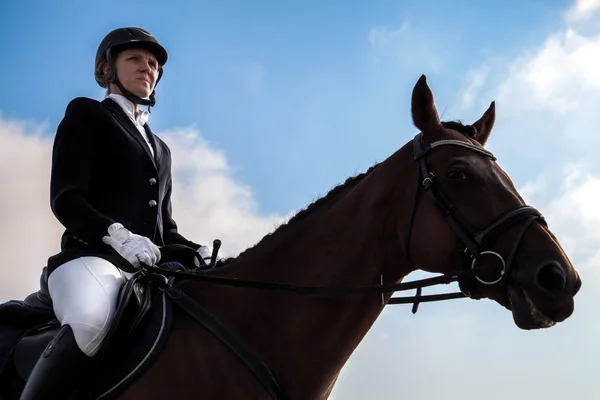 Серйозна жокейна жінка сидить на коні . — стокове фото