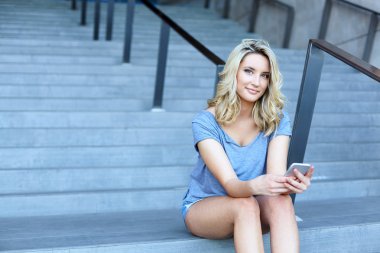 Hareket eden telefon ile çalışma ve merdivenlerde oturan genç kız