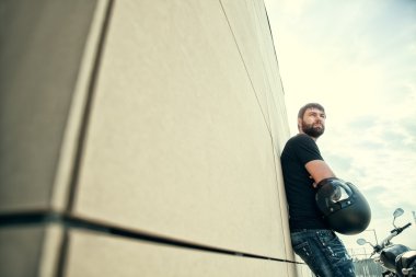 Motorcu erkekler siyah gömlek ayakta duvarının yakınında sakallı