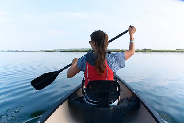 在炎热的夏天在湖中划独木舟的年轻女人. — 图库照片