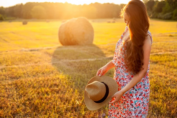 Mujer en sombrero con pelo rizado de pie en el campo —  Fotos de Stock