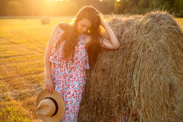 美丽的女人站在字段中的一捆草. — 图库照片