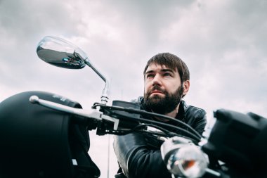 Biker with a beard on his motorcycle in the leather jacket