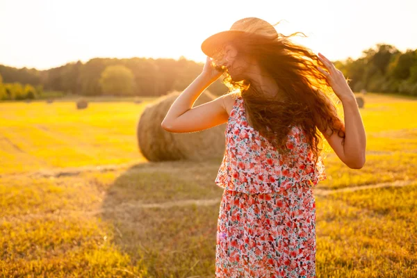 Женщина в шляпе с вьющимися волосами двигается вверх в поле — стоковое фото